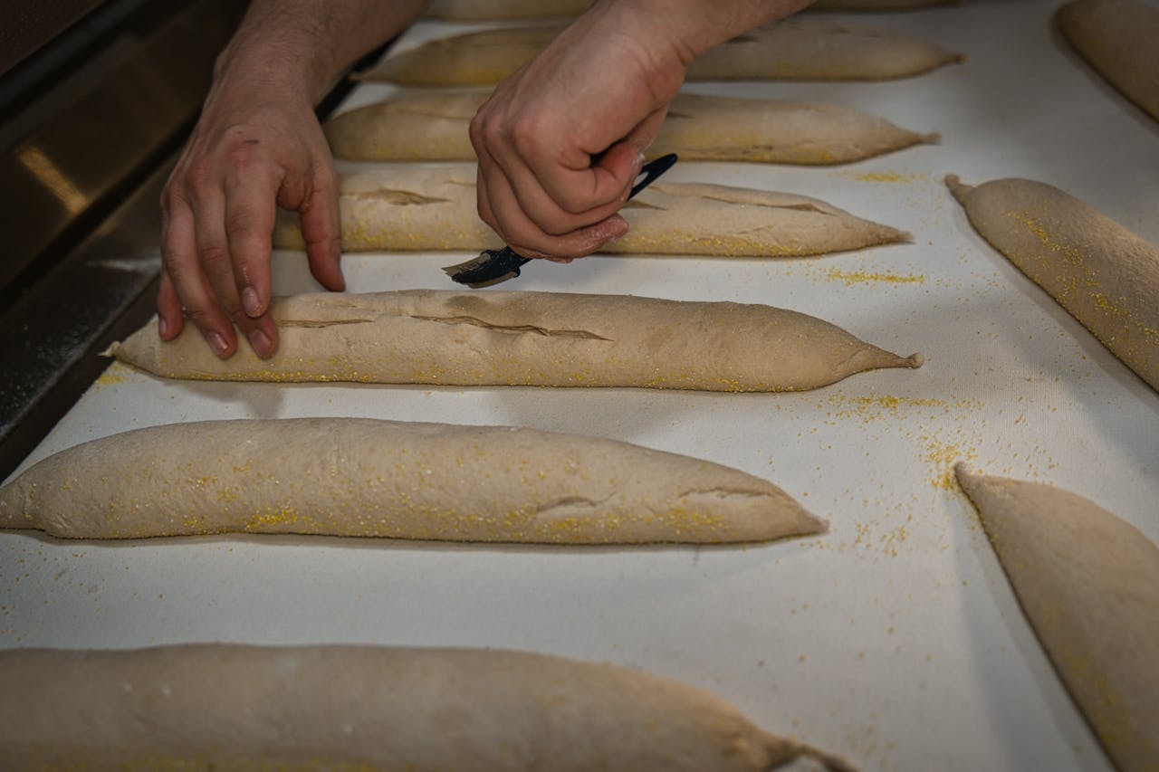 Hands crafting artisan bread loaves, showcasing traditional baking techniques in a Berlin bakery.